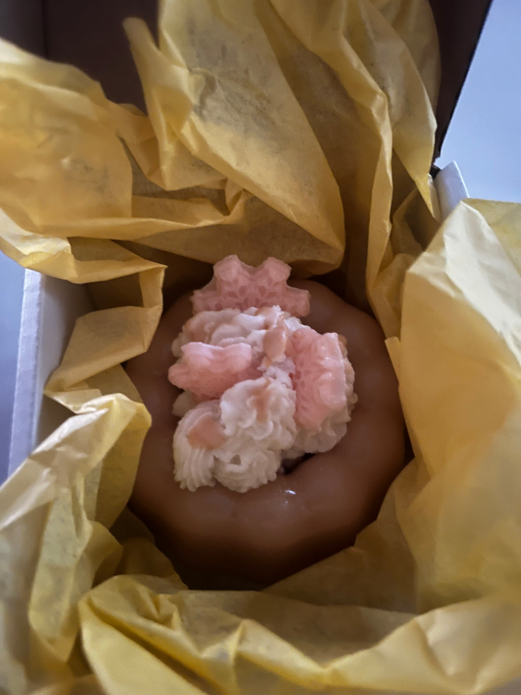 Pink, lemon yellow and white wax bundt cake wrapped in yellow tissue paper.